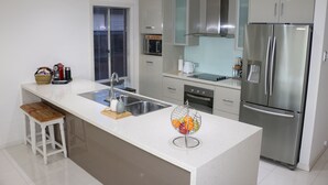 A modern kitchen with a large island, stainless steel appliances, and a window with blinds.