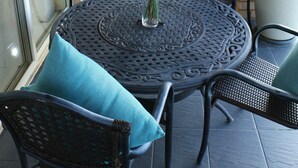 A patio with a round table, chairs, and a vase of flowers.