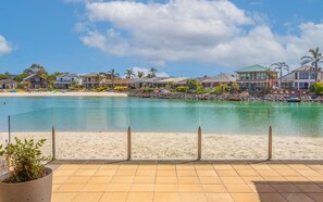 A beachfront property with a clear view of the sea, a sandy beach, and a row of houses with a rocky shoreline. - 'Secrets of the Sea' - 3BR luxury home overlooking a lagoon with private beach  (Encounter Bay)