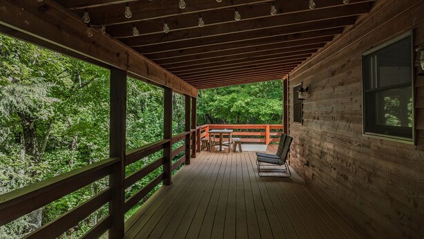 Une terrasse en bois avec une rambarde, une table et deux chaises.