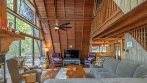 A spacious living room with a wooden ceiling, a large TV, comfortable seating, and a fireplace. - The Foxtail Overlook by Innsbrook Vacations! (Innsbrook)