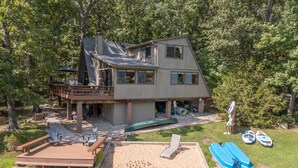 A two-story cabin with a deck, a sandy area, and a small boat dock. - The Foxtail Overlook by Innsbrook Vacations! (Innsbrook)