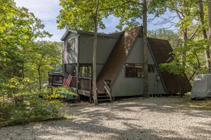Une cabane dotée d’une terrasse en bois, d’un escalier et d’un espace abrité.