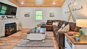 Ein gemütliches Wohnzimmer mit Kamin, einer braunen Ledersofa, einem Couchtisch und einem Wand-Fernseher.