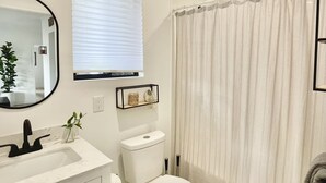 Un baño con un lavabo blanco, inodoro, cortina de ducha y espejo.