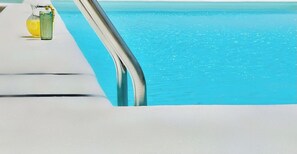 A poolside area with a clear view of the water and a glass of a yellow beverage. - Canaryislandshost l Mare (Puerto del Carmen)