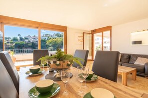 A dining area with a table set for four, a sofa, and a view of the landscape.
