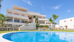 Un hôtel moderne doté d’une piscine, de nombreux balcons et offrant une vue sur un ciel d’un bleu éclatant.