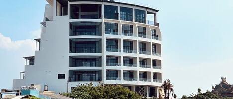 A multi-story building with a modern architectural design, featuring a series of balconies and large windows.