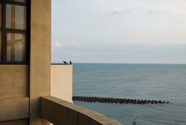 Un balcón con vistas al mar y un espigón rocoso.