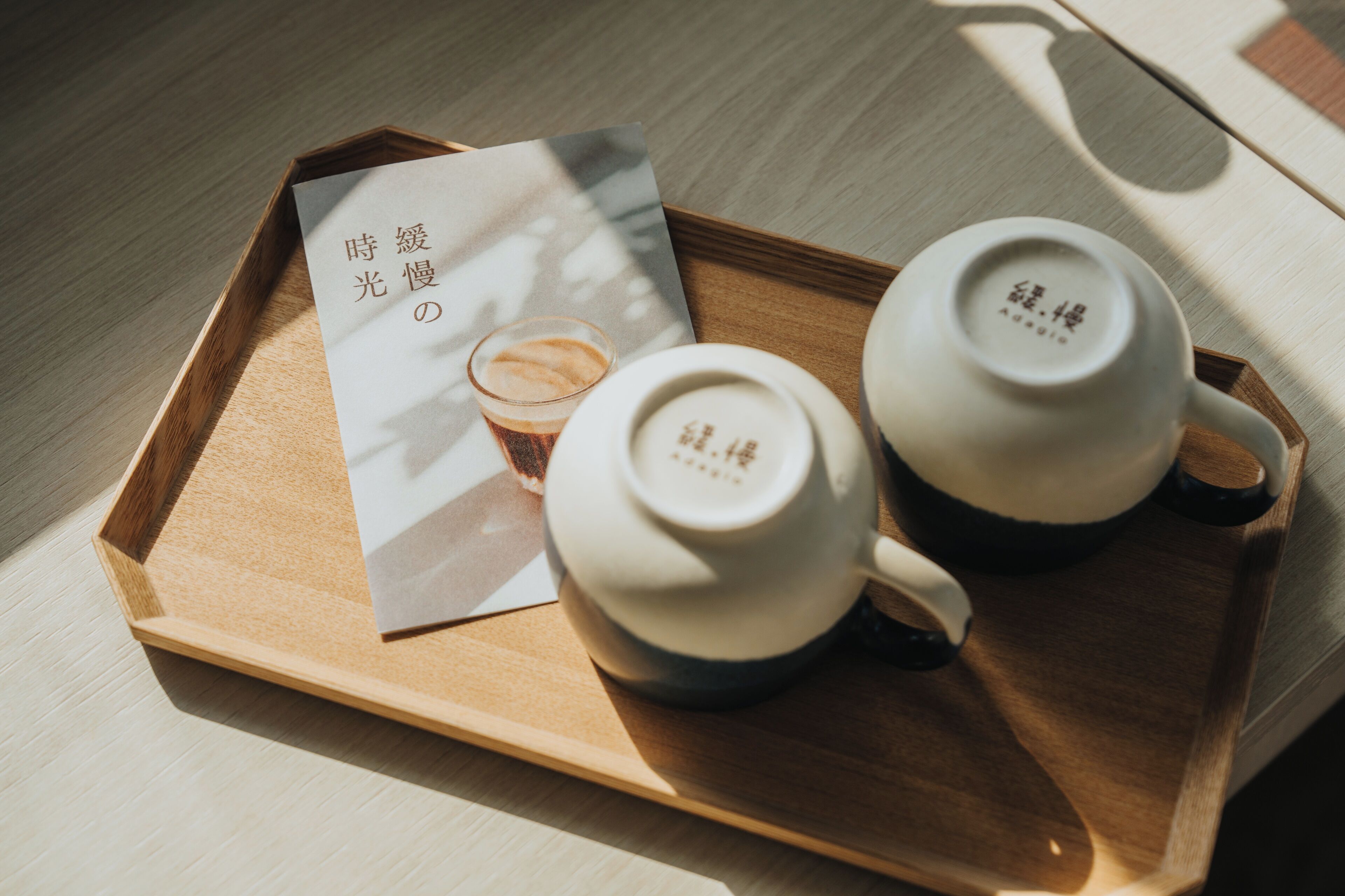 A wooden tray with two teapots and a cup of tea, accompanied by a card with Japanese text.