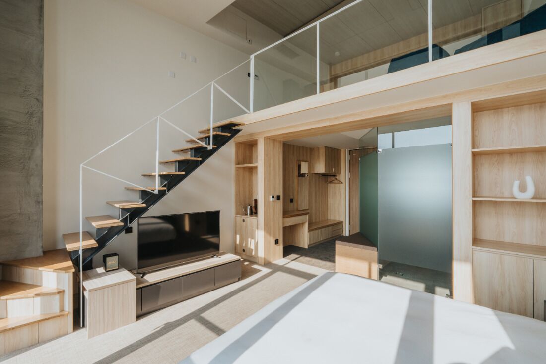 Un interior moderno con una escalera, estanterías de madera y un televisor de pantalla plana.