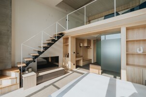 Un interior moderno con una escalera, estanterías de madera y un televisor de pantalla plana.
