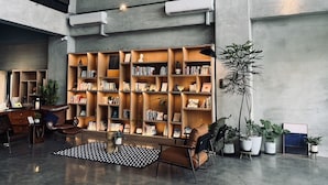 A spacious lobby with a large bookshelf, leather chairs, and potted plants.