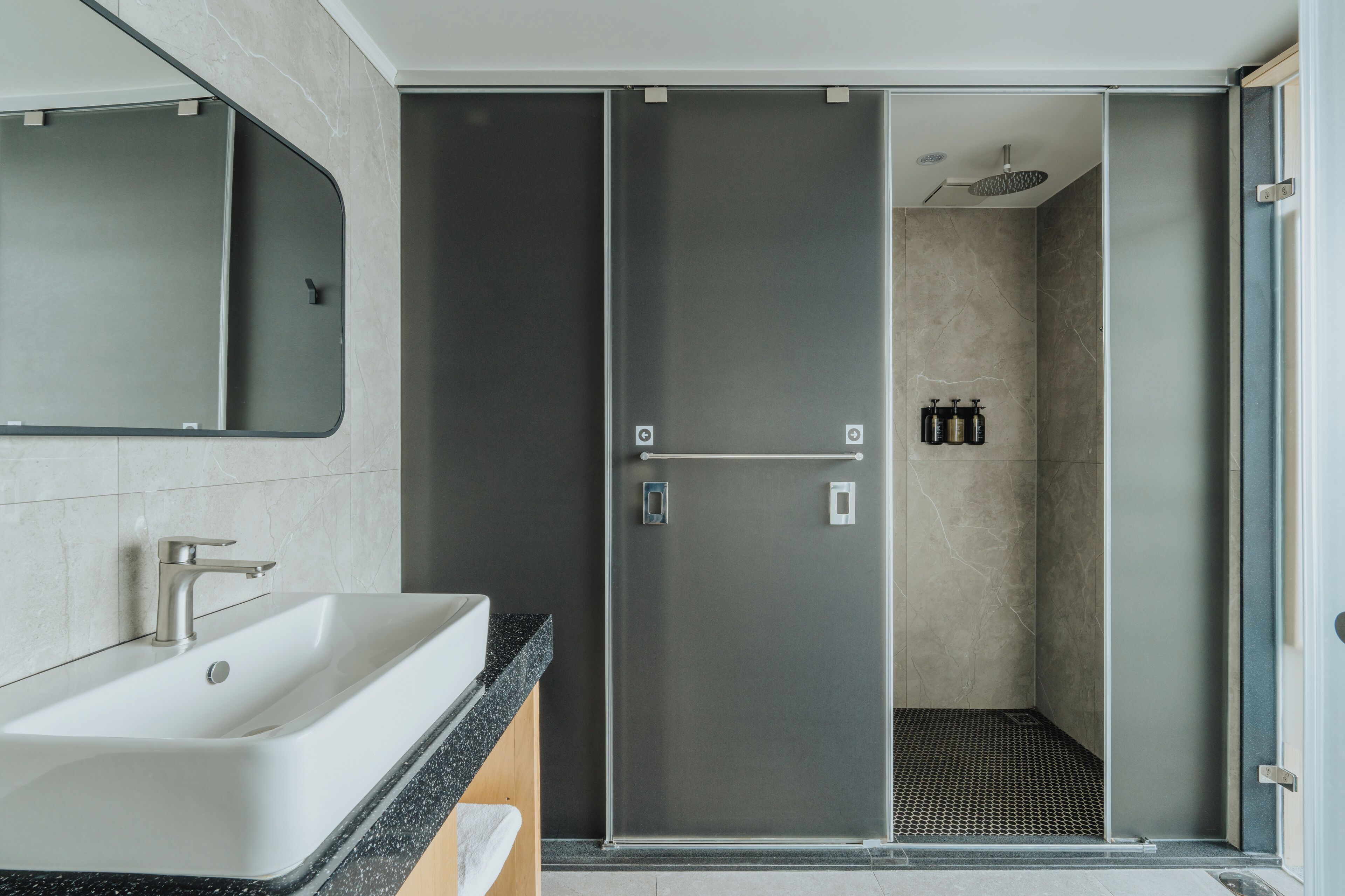 Un baño moderno con un lavamanos grande, un espejo y una ducha a ras de suelo.