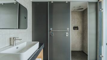 Un baño moderno con un lavamanos grande, un espejo y una ducha a ras de suelo.