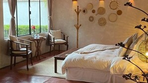 A bedroom with a bed, two chairs, a small table, and a decorative wall.