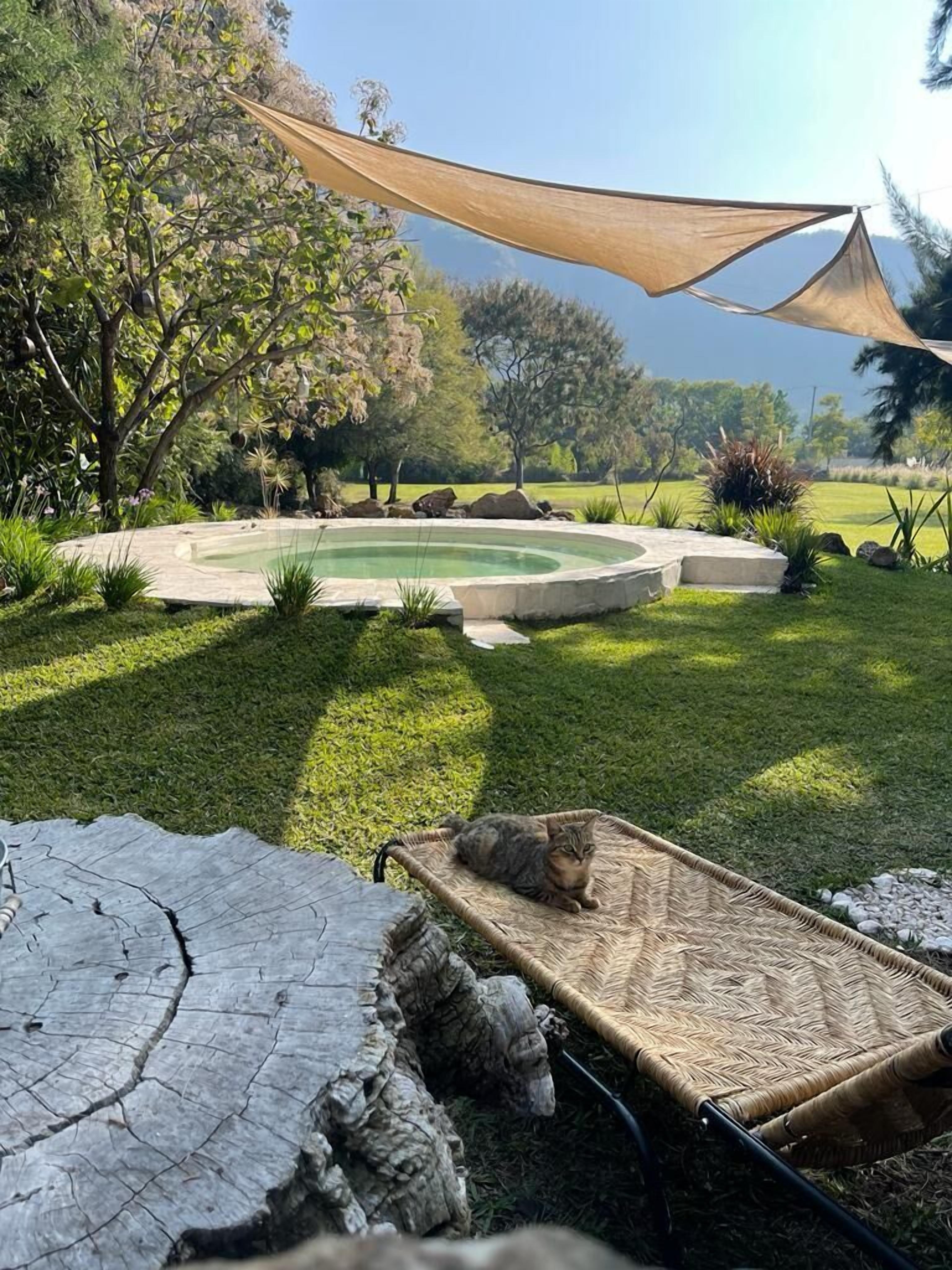 Patio con piscina circular, una hamaca y un espacio con sombra.