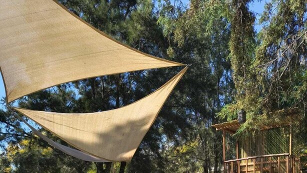 A pool area with a stone deck, lounge chairs, and a wooden deck structure.