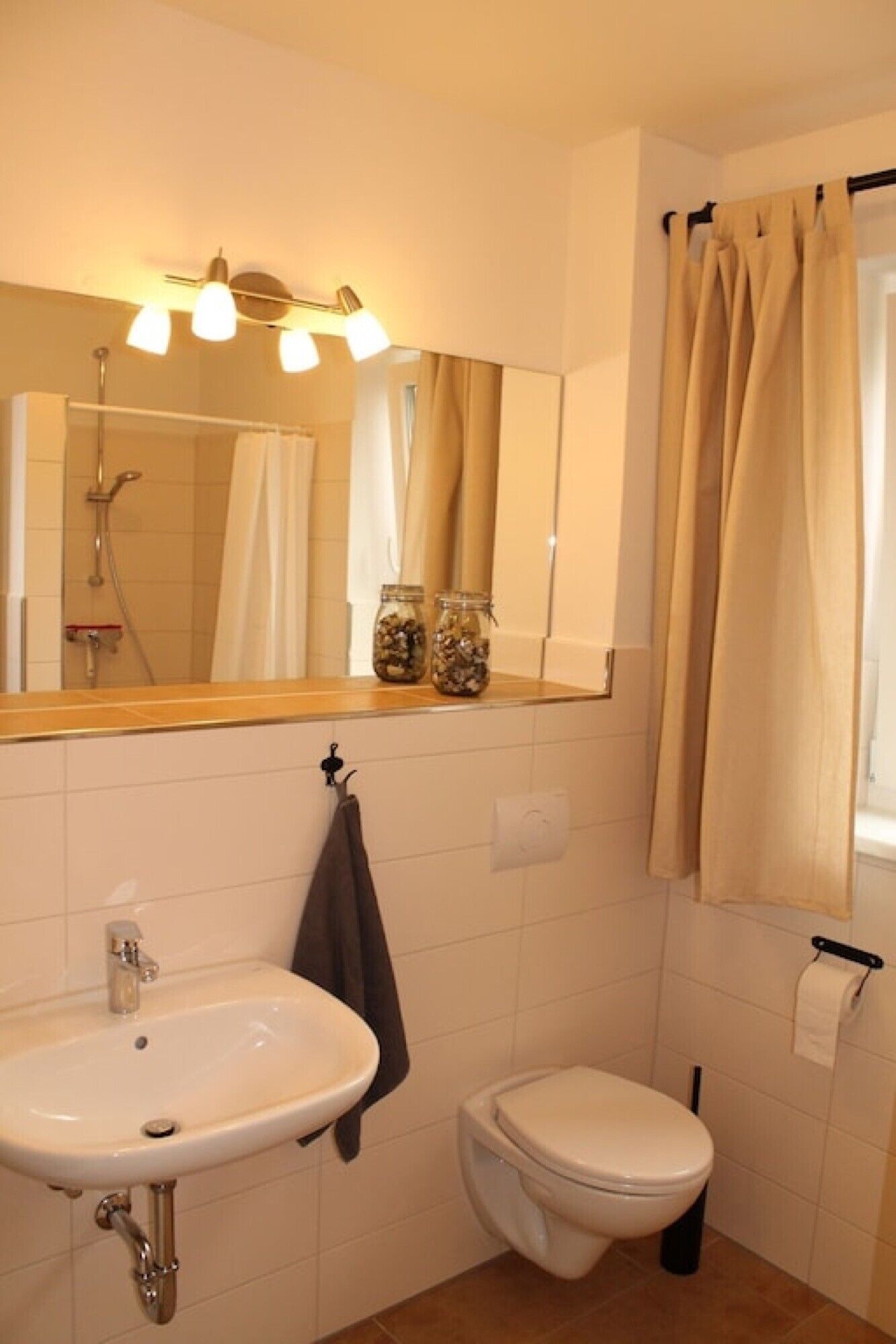 Ein Badezimmer mit Waschbecken, Toilette und Dusche. Auf dem Waschbecken stehen Flaschen.