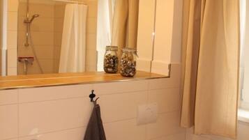 Ein Badezimmer mit Waschbecken, Toilette und Dusche. Auf dem Waschbecken stehen Flaschen.