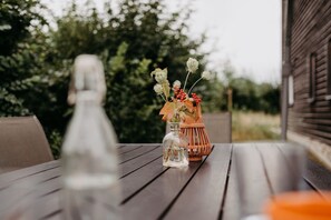 A wooden table with a vase of flowers and a glass bottle.