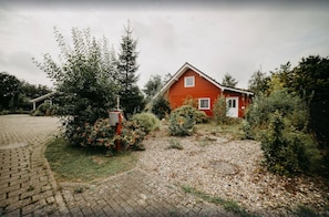 Ein rotes Haus mit kleinem Garten und gepflasterter Auffahrt.