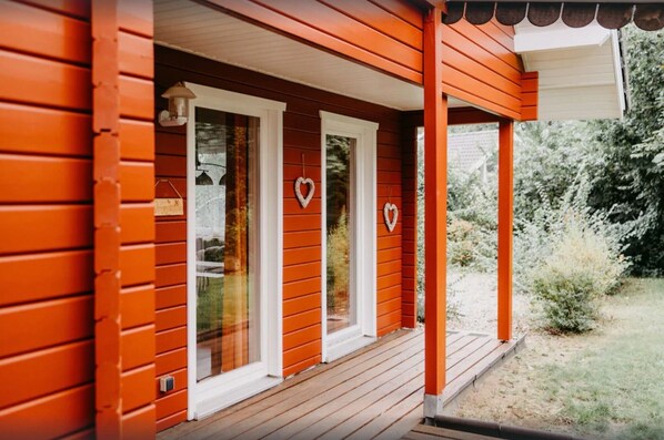 Una casa de madera con un porche, ventanas de marco blanco y decoraciones con forma de corazón.
