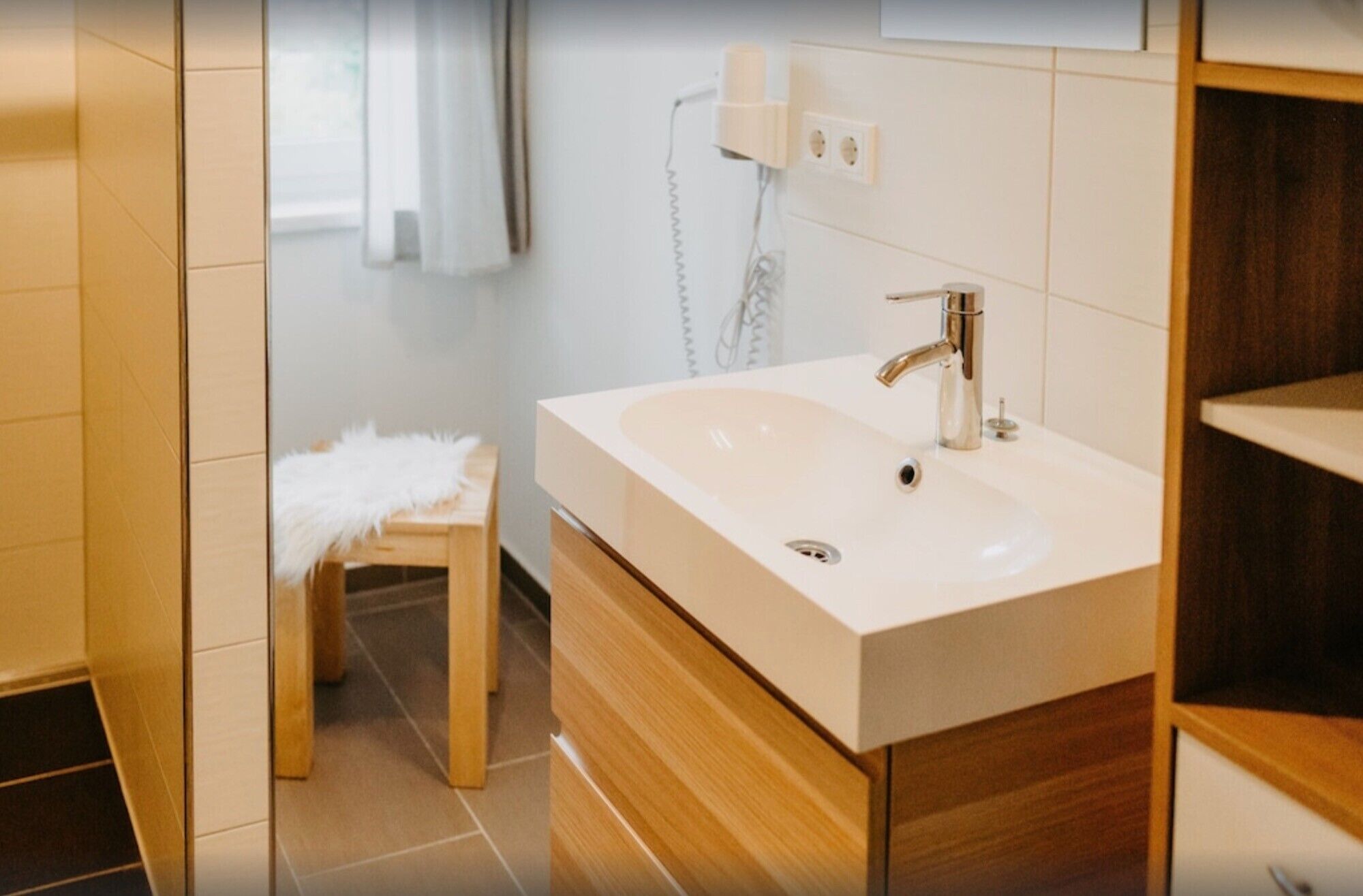 Een moderne badkamer met een groot wastafel, een spiegel en een handdoek op een kruk.