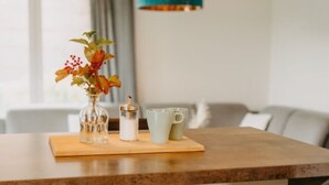 Un coin repas avec une table en bois, un vase de fleurs, un salier et une tasse.