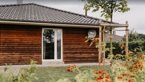 Une maison en bois avec un toit recouvert de tuiles, une porte bien visible et une antenne parabolique.