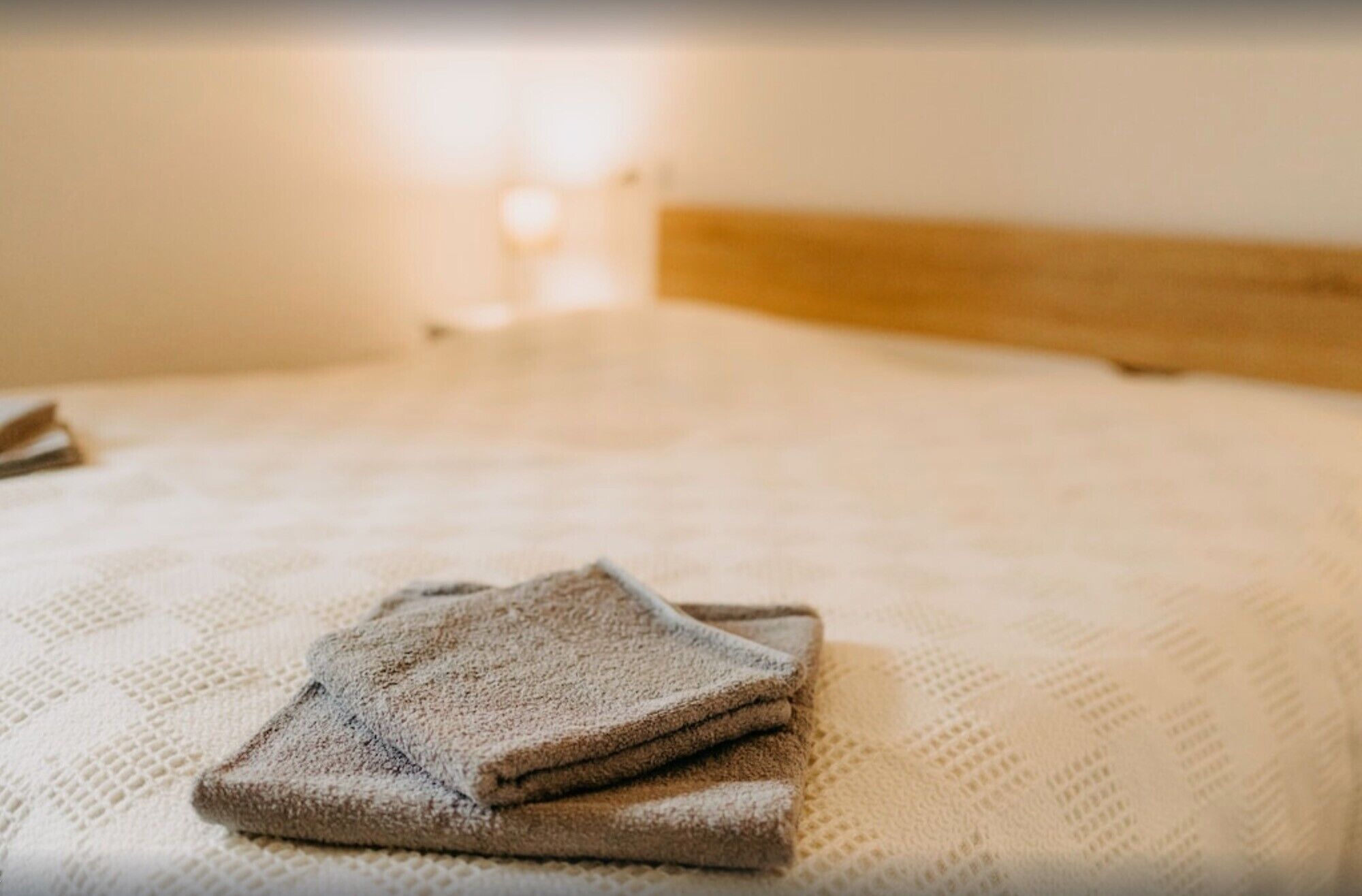Ein ordentlich bezogenes Bett mit einem gefalteten Handtuch darauf.