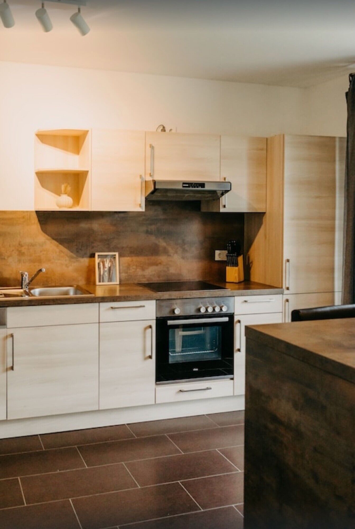 Una cocina moderna con horno empotrado, un lavamanos y armarios de madera.