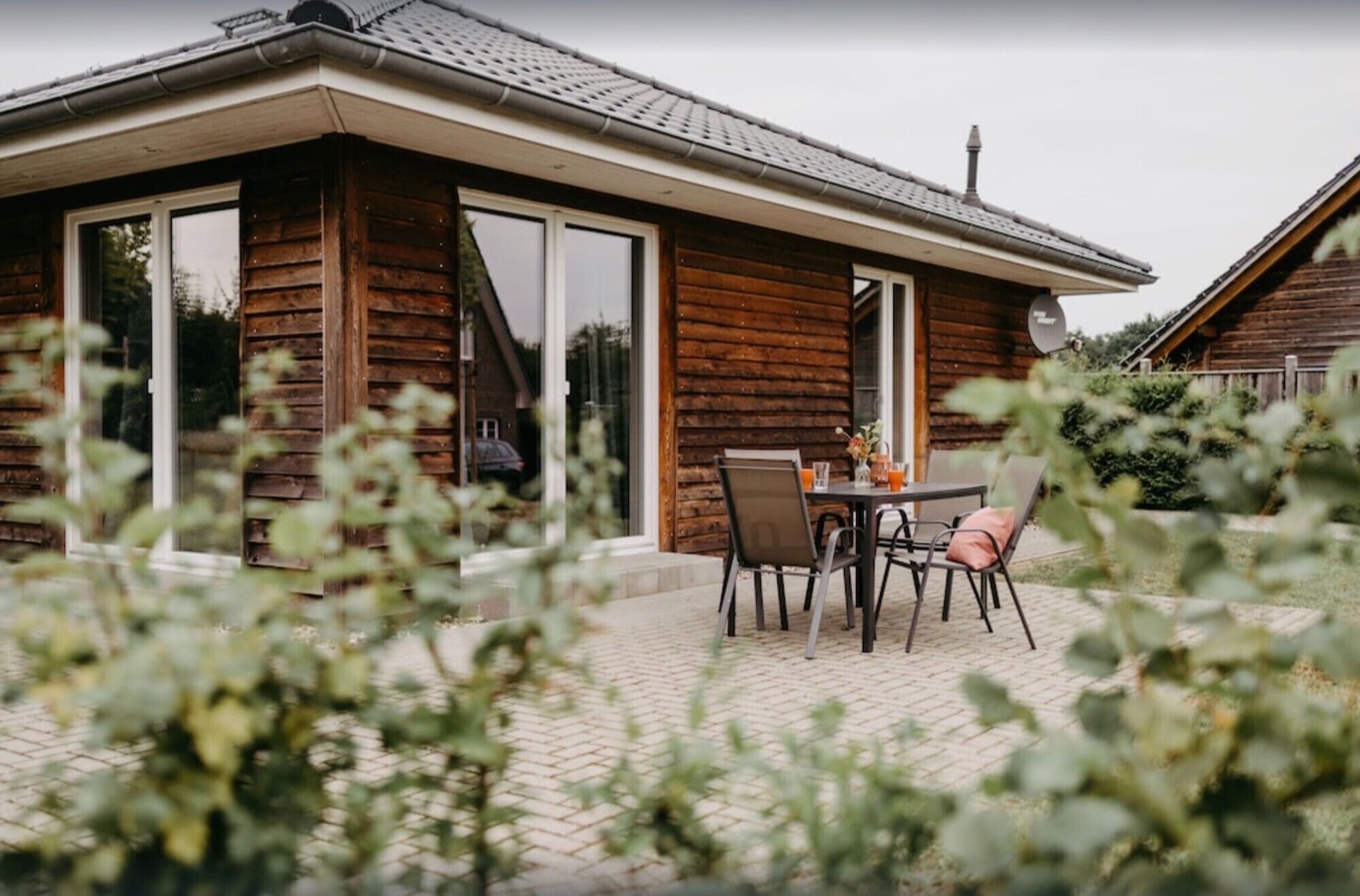 En stuga byggd av trä med en uteplats, skjutdörrar i glas och en satellantenn.