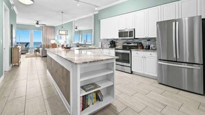 A modern kitchen with white cabinets, stainless steel appliances, and a central island with books.