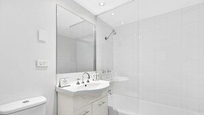 Ein modernes Badezimmer mit einem weißen Waschbecken, einem Spiegel und einer Toilette.