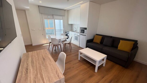 Un salon moderne avec un coin repas, un canapé et une cuisine en arrière-plan.