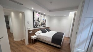 Une chambre à coucher moderne avec un grand lit, une table de chevet et une œuvre d’art accrochée au mur.