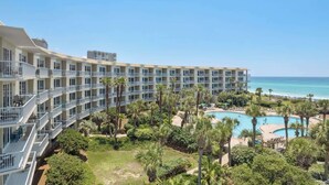 A hotel with multiple balconies, a pool area, and a view of the ocean.