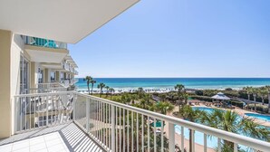 A balcony with a view of a beach and a pool.