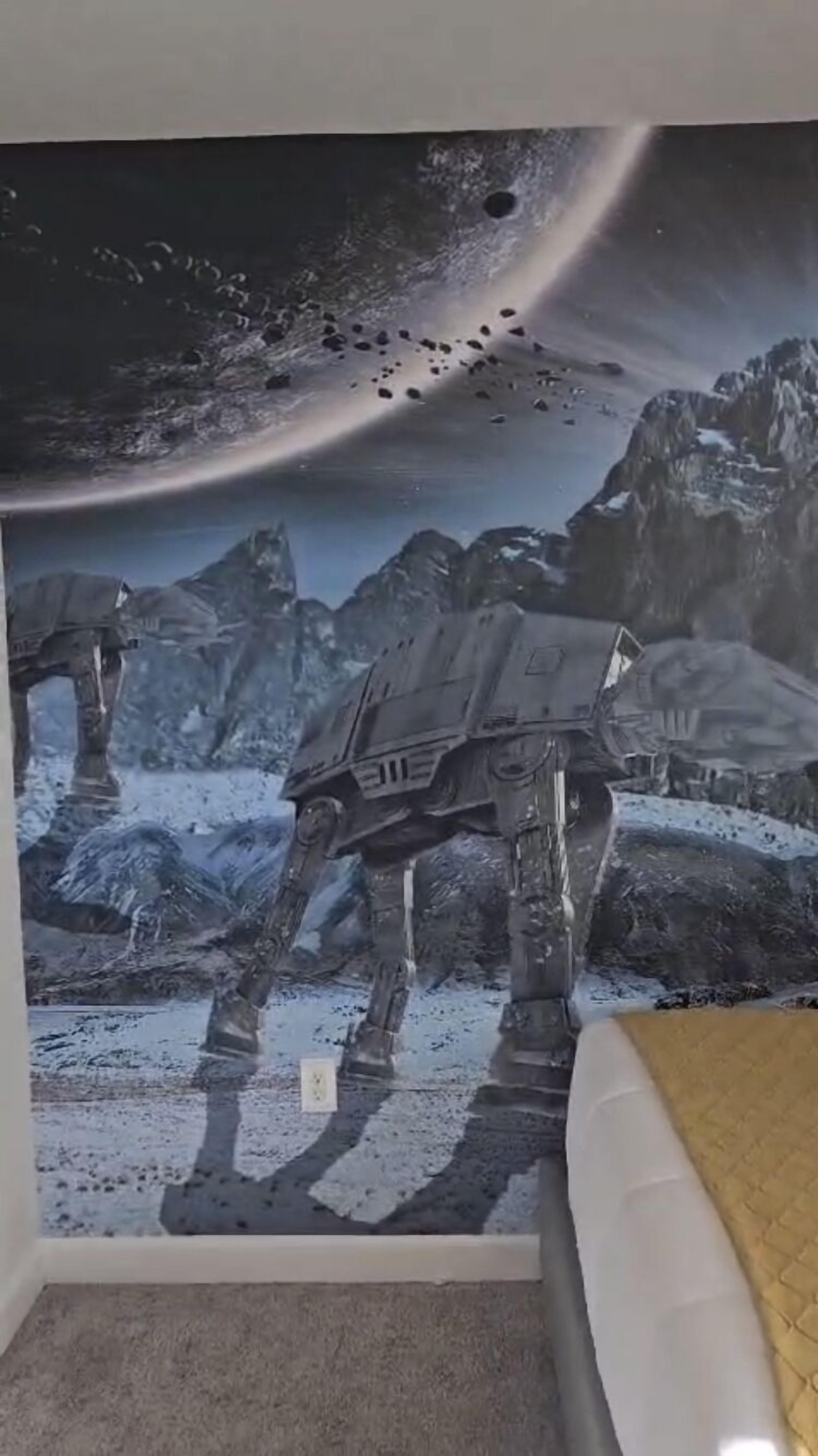 Una stanza con un murale raffigurante una scena spaziale con un’astronave di grandi dimensioni.