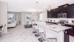 Una cocina moderna con armarios oscuros, una isla grande y electrodomésticos de acero inoxidable.