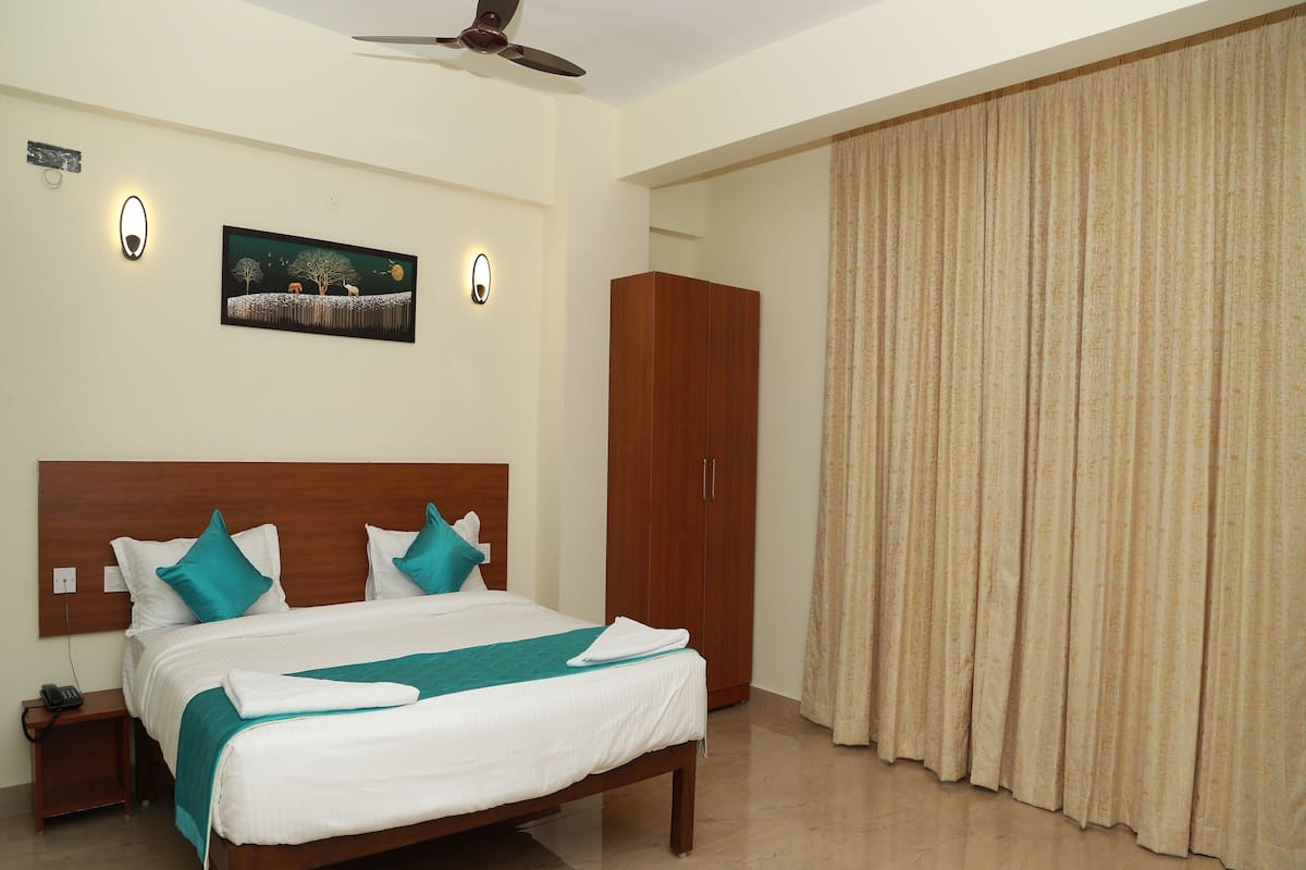 A hotel room with a bed, a wardrobe, a painting, and a ceiling fan.