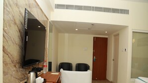 A hotel room with a wooden desk, a flat-screen TV, a sofa, and a bed. - Royal Chola (Sriperumbudur)