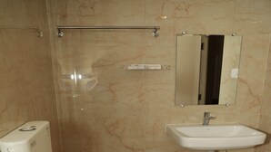 A bathroom with a toilet, a sink, a hand dryer, and a mirror. - Royal Chola (Sriperumbudur)