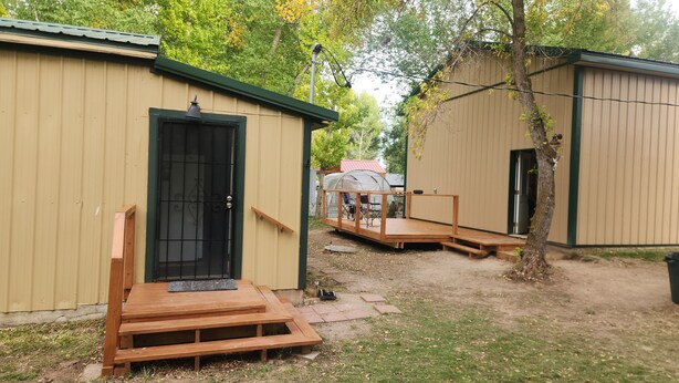 Un pequeño espacio al aire libre con un banco de madera, una zona de estar techada y una reja de metal.