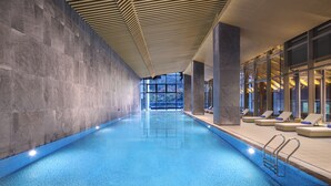 An indoor swimming pool with a modern design, featuring a long, narrow layout and a ceiling with a geometric pattern. - NBICC Wonderland Hotel (Ningbo)