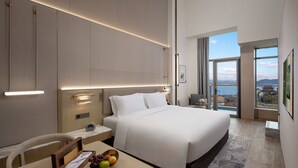 A modern hotel room with a large bed, bedside table, and a bowl of fruit. - NBICC Wonderland Hotel (Ningbo)