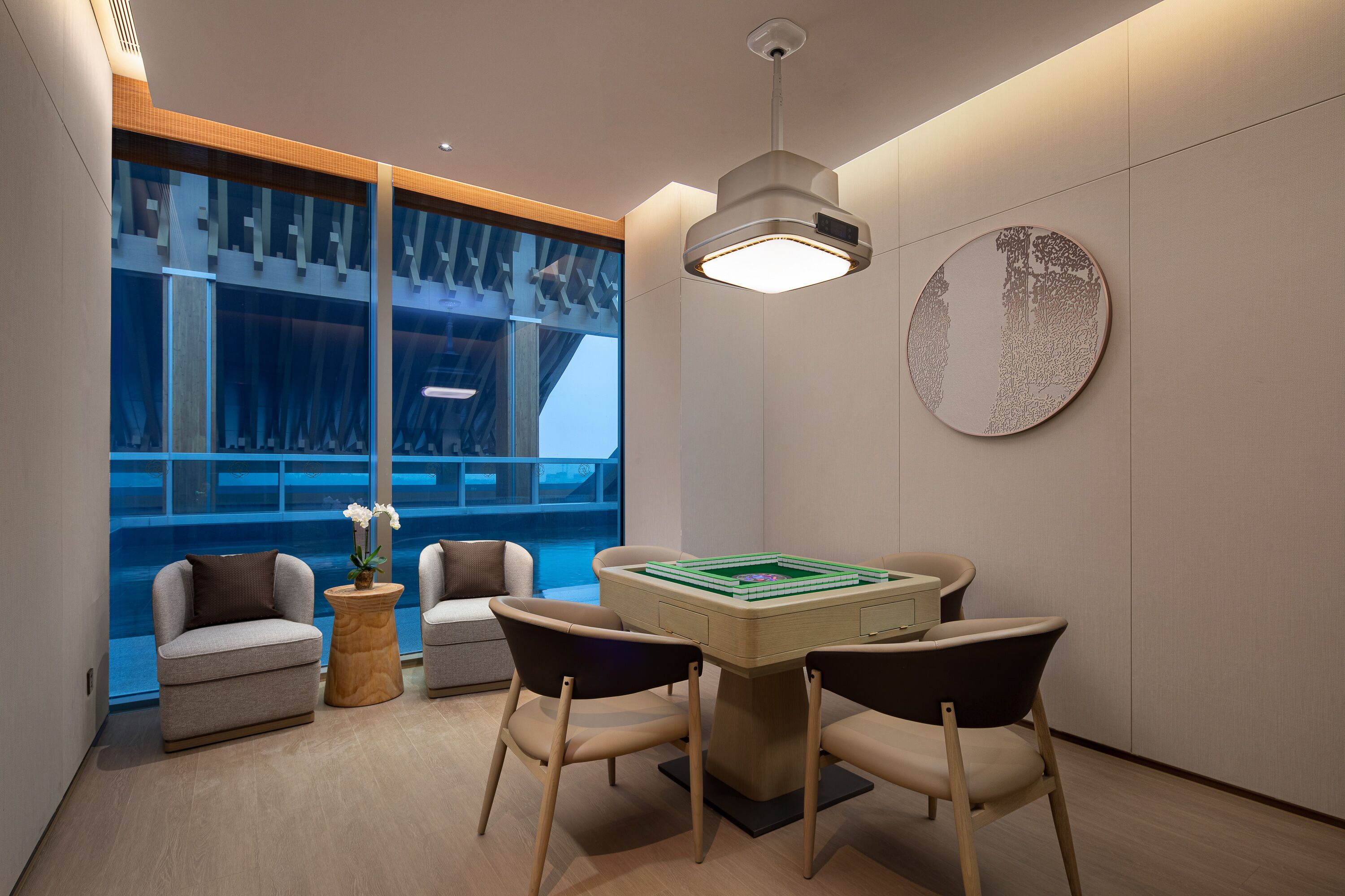 Une chambre moderne avec vue sur la piscine, une table ronde avec des chaises et une œuvre d’art murale originale.