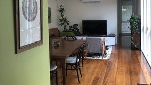 Ein geräumiger Wohnbereich mit Esstisch, Stühlen, einer Couch und einem Flachbildfernseher.